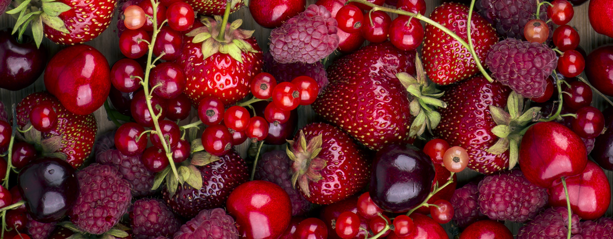 A close-up of fresh red strawberries, cherries, raspberries and huckleberries.